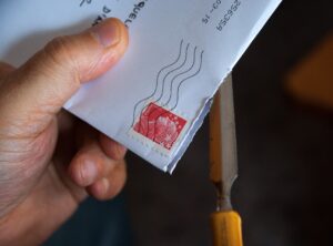 Immagine di una mano che porge una lettera con francobollo