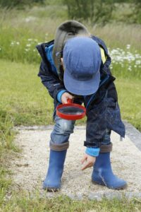 Bambino con lente di ingrandimento esplora il terreno